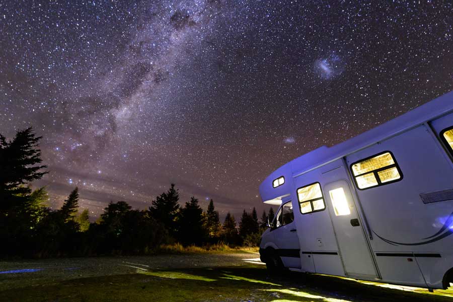 Motorhome parked in field underneath stars